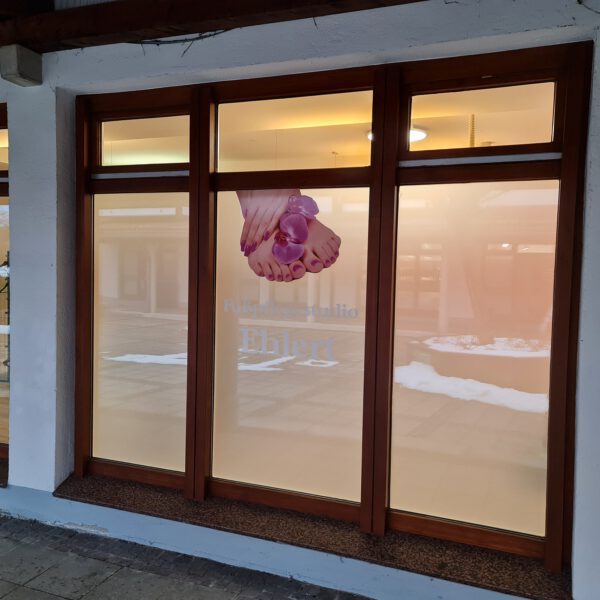 Eine Auswahl an farbigen und bedruckten Milchglasfolien für Fenster und Flachglas, die als Sichtschutz dienen. Eine Folie ist mit einem Firmenlogo bedruckt und zeigt die hochwertigen Gestaltungsmöglichkeiten von c&w - das Werbezentrum.